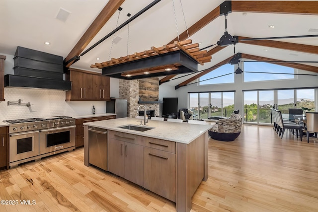 5780 Wildridge Rd E Unit A, Avon, CO 81620 - kitchen with stainless steel appliances, a sink, open floor plan, custom range hood, and beamed ceiling
