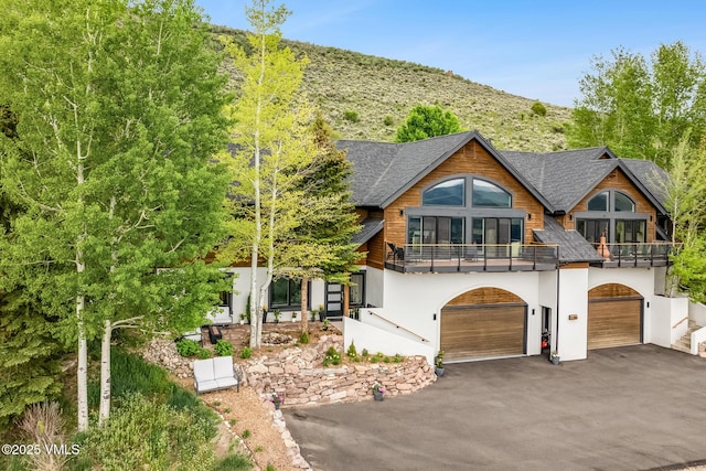 5780 Wildridge Rd E Unit A, Avon, CO 81620 - rustic home featuring a balcony, driveway, an attached garage, stucco siding, and a mountain view