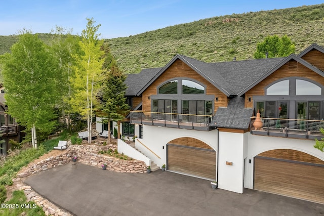 5780 Wildridge Rd E Unit A, Avon, CO 81620 - chalet / cabin with a balcony, asphalt driveway, a garage, stucco siding, and roof with shingles
