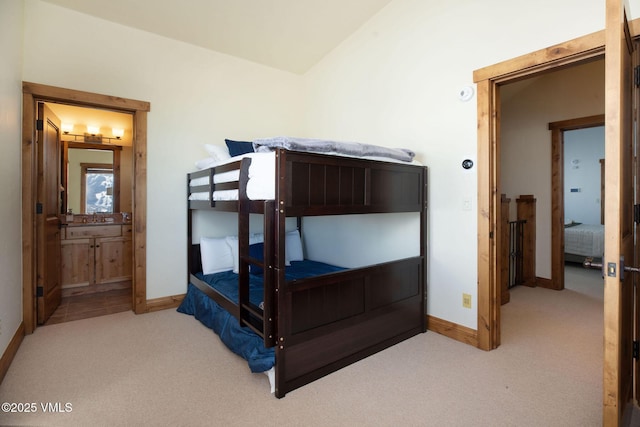 bedroom featuring light carpet, ensuite bath, baseboards, and a sink