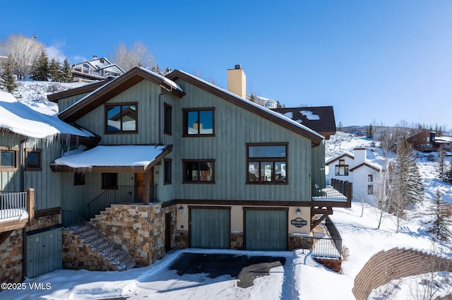 chalet / cabin with a garage, stone siding, a chimney, and stairway