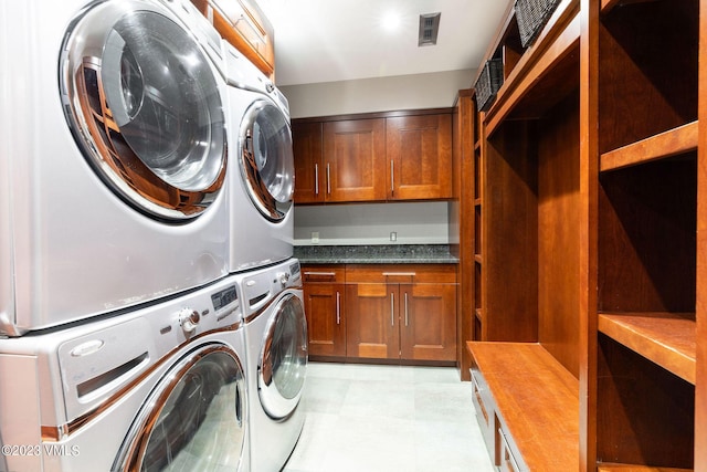 laundry room featuring cabinets and stacked washer / dryer