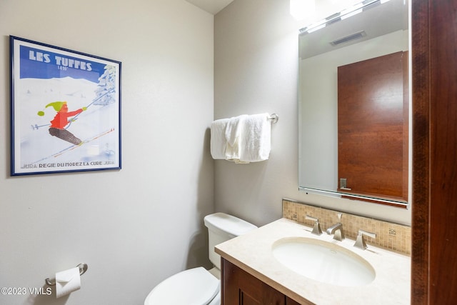 bathroom featuring vanity, toilet, and decorative backsplash