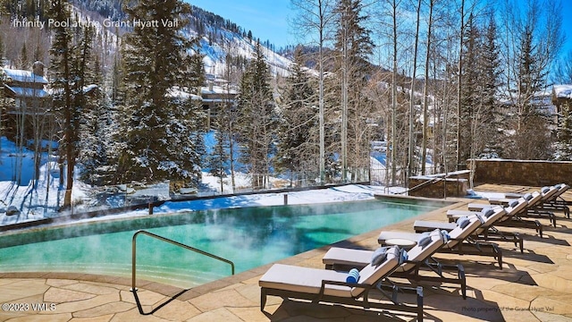 snow covered pool with a mountain view and a patio area