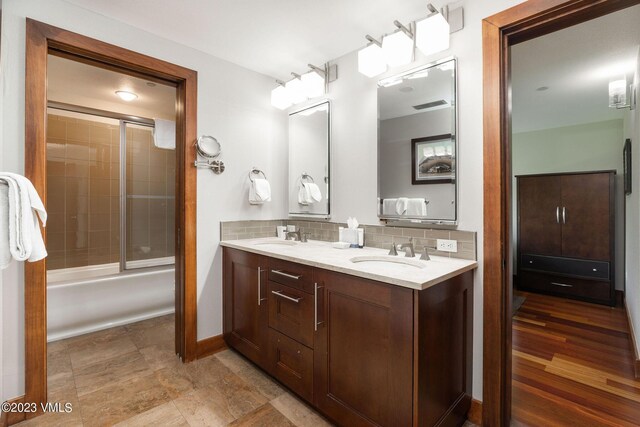 bathroom featuring vanity, combined bath / shower with glass door, and backsplash