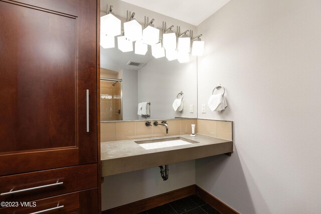 bathroom with tasteful backsplash, tile patterned floors, sink, and a shower