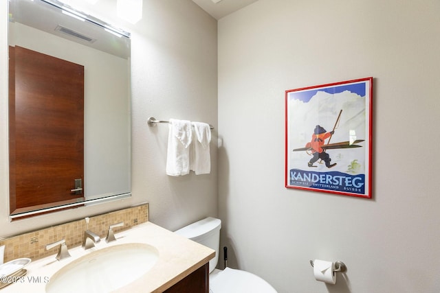 bathroom featuring tasteful backsplash, vanity, and toilet