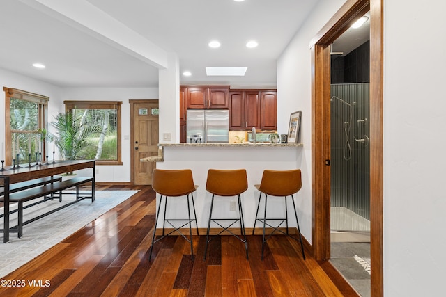 4254 Columbine Way Unit 9, Vail, CO 81657 - kitchen featuring stainless steel fridge, dark wood-type flooring, a breakfast bar, recessed lighting, and a skylight