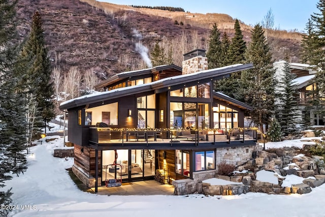 snow covered back of property with a deck with mountain view