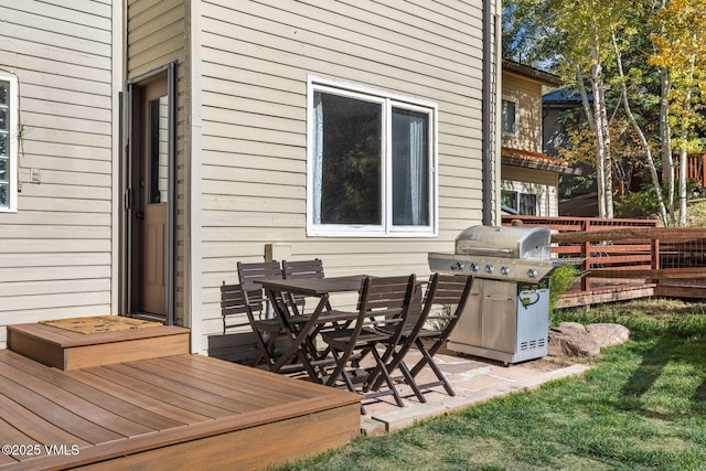 wooden terrace featuring a grill, fence, and a patio