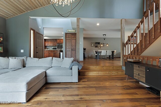 living room with wood finished floors, recessed lighting, a chandelier, vaulted ceiling, and stairs