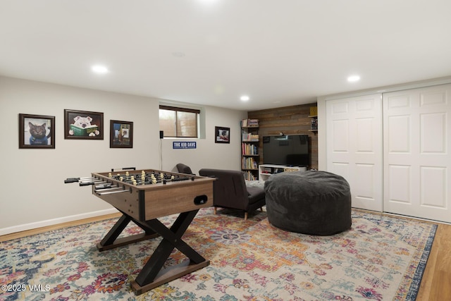recreation room with wood finished floors, recessed lighting, baseboards, and wood walls