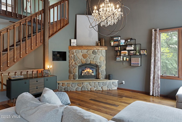 living area featuring wood finished floors, a chandelier, stairs, a fireplace, and baseboards