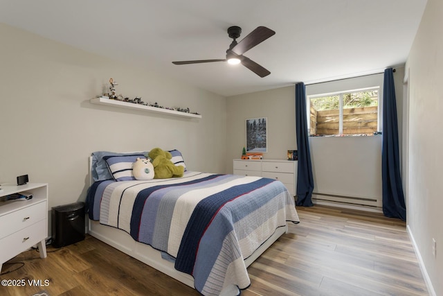 bedroom featuring a baseboard heating unit, light wood finished floors, and ceiling fan