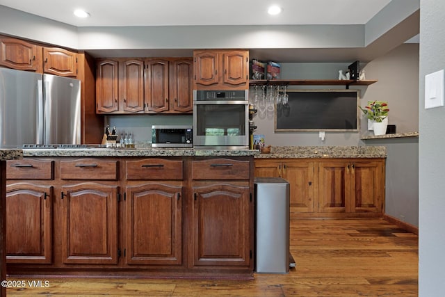 kitchen with stainless steel appliances, light wood-style floors, light stone countertops, brown cabinetry, and recessed lighting
