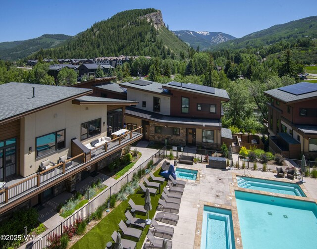 42 Riverfront Ln Unit 304, Avon, CO 81620 - rear view of property featuring a hot tub, a mountain view, a fenced backyard, and an outdoor living space