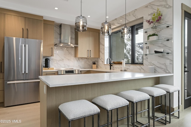 42 Riverfront Ln Unit 304, Avon, CO 81620 - kitchen featuring freestanding refrigerator, wall chimney exhaust hood, light countertops, a breakfast bar area, and recessed lighting