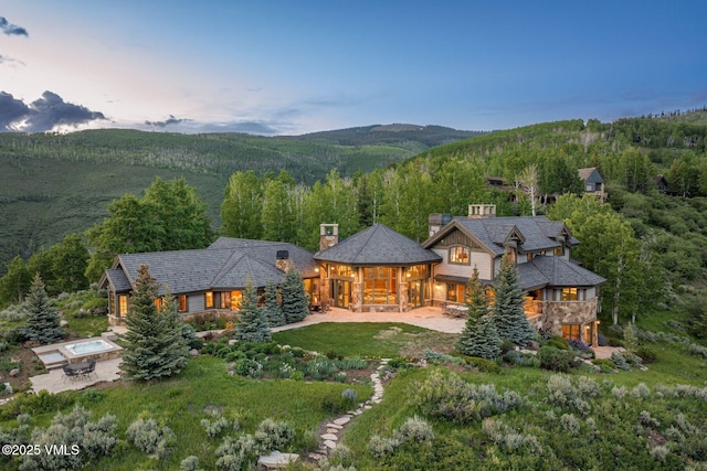 1006 Chiming Bells, Avon, CO 81620 - back of property featuring a chimney, a forest view, a patio area, a mountain view, and stone siding