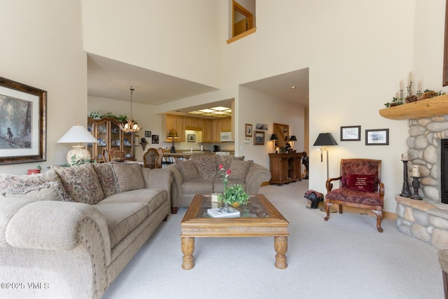 living room with light carpet, a high ceiling, a chandelier, and a fireplace