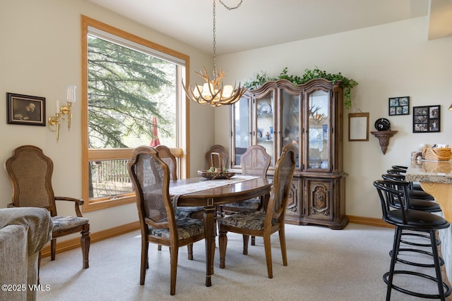 dining space featuring a chandelier, light carpet, and baseboards