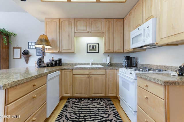 kitchen featuring light brown cabinetry, white appliances, a sink, and light wood finished floors