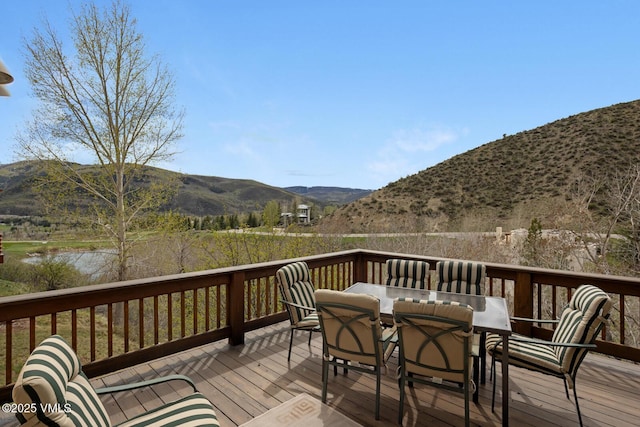 wooden terrace featuring a mountain view and outdoor dining space