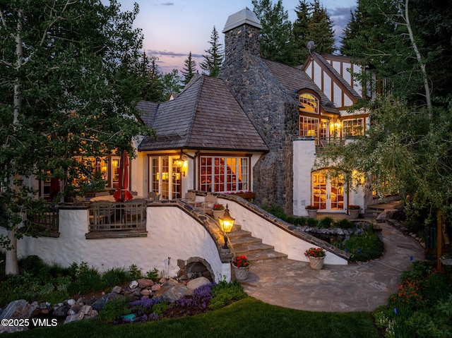 443 Beaver Dam Rd, Vail, CO 81657 - back of property at dusk featuring french doors, stucco siding, a patio area, and a chimney