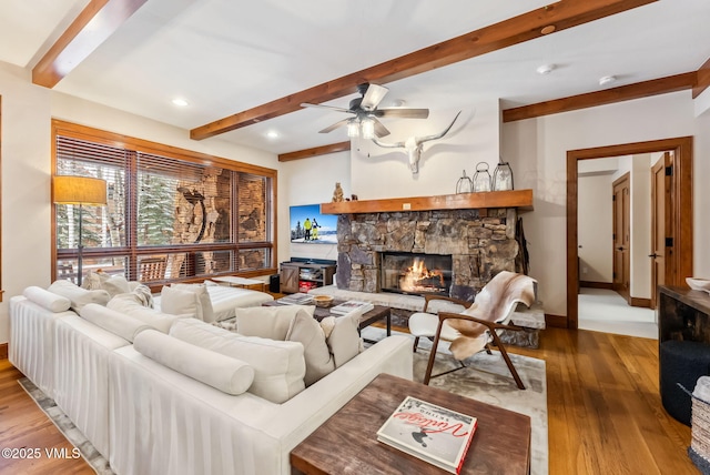205 Bear Paw Unit B102, Avon, CO 81620 - living room featuring ceiling fan, beam ceiling, a stone fireplace, baseboards, and wood finished floors