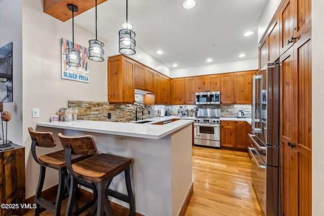 205 Bear Paw Unit B102, Avon, CO 81620 - kitchen featuring light wood finished floors, a kitchen breakfast bar, a peninsula, decorative backsplash, and premium appliances