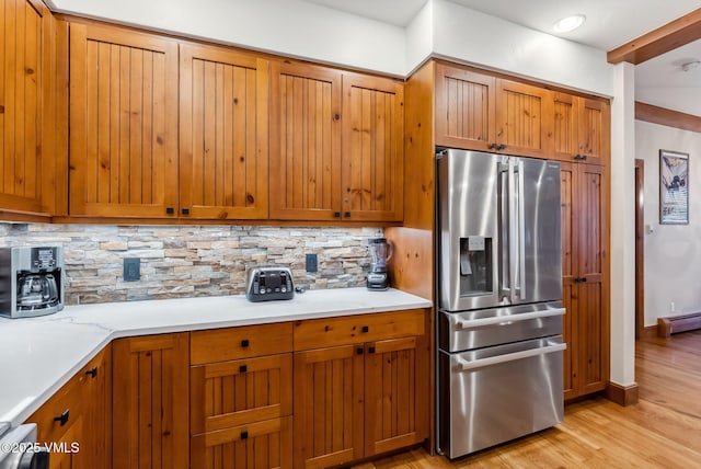 205 Bear Paw Unit B102, Avon, CO 81620 - kitchen featuring stainless steel refrigerator with ice dispenser, brown cabinetry, light wood finished floors, and backsplash