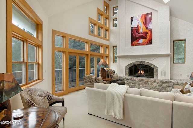 carpeted living room with a fireplace and high vaulted ceiling