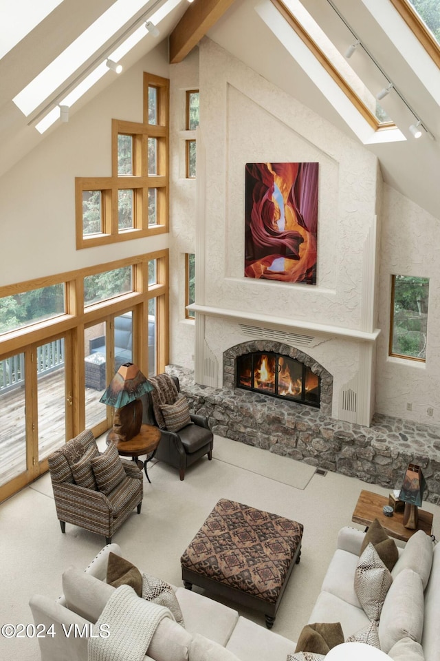 living room with track lighting, a fireplace, a skylight, and high vaulted ceiling