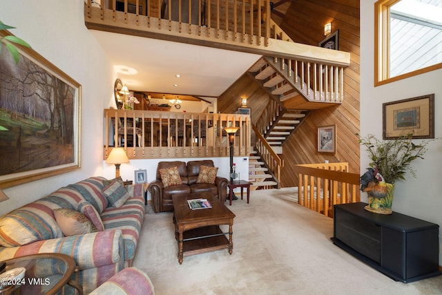 living room featuring wooden walls, carpet, and a high ceiling