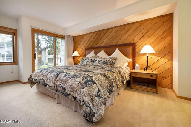 bedroom featuring light colored carpet, access to outside, multiple windows, and wood walls