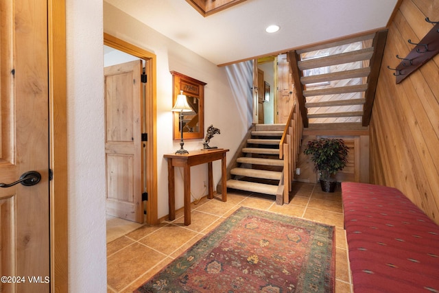 stairs featuring tile patterned floors and wood walls