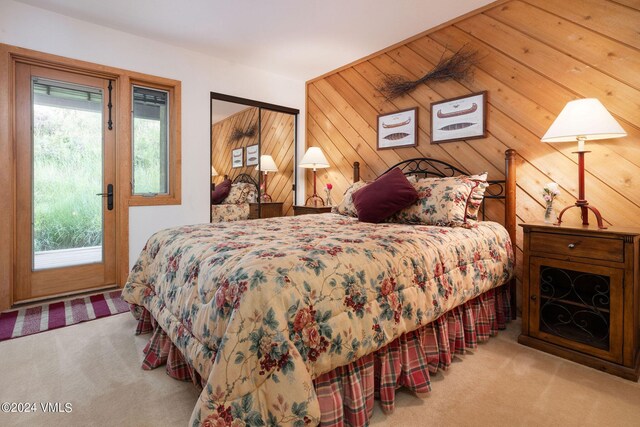 carpeted bedroom featuring multiple windows, access to outside, and wood walls