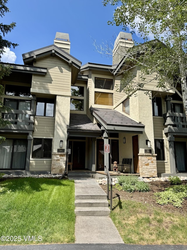 186 Willis Pl Unit 186, Beaver Creek, CO 81620 - view of front facade with a chimney, a front lawn, and stucco siding
