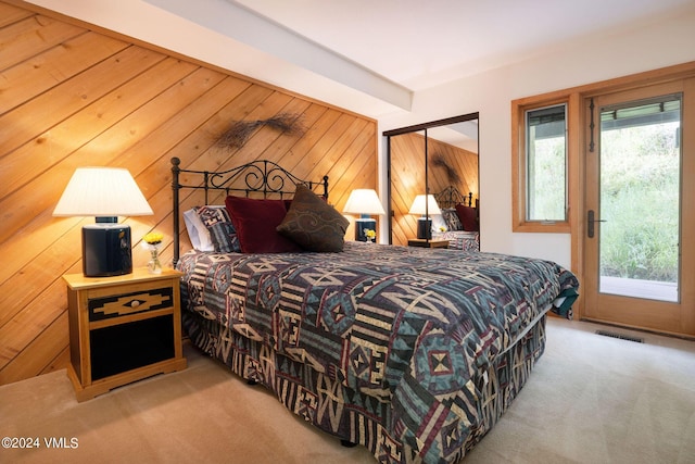 carpeted bedroom with wooden walls, access to exterior, and a closet