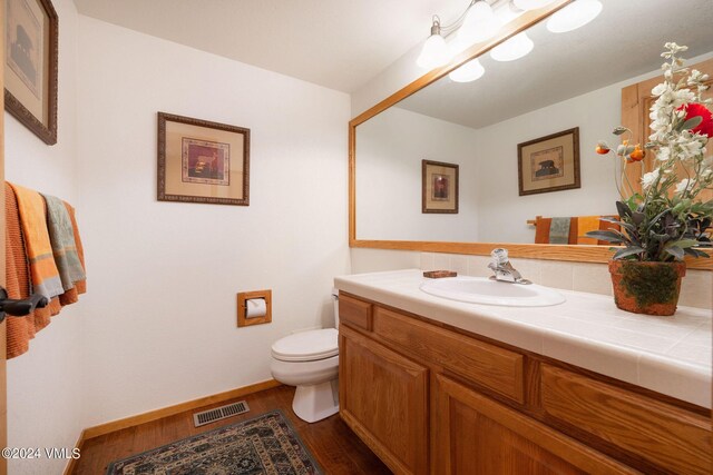 bathroom featuring wood-type flooring, toilet, and vanity