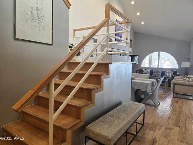 stairway with high vaulted ceiling and hardwood / wood-style floors