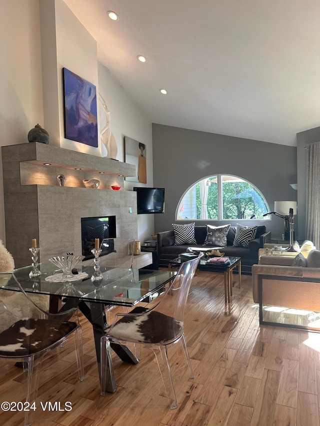 living room with lofted ceiling, a fireplace, and light hardwood / wood-style floors