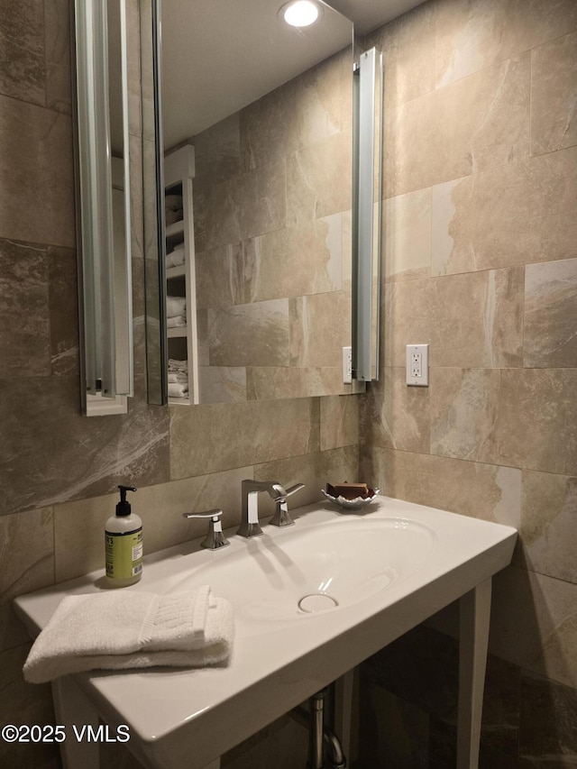 bathroom with tasteful backsplash, sink, and tile walls