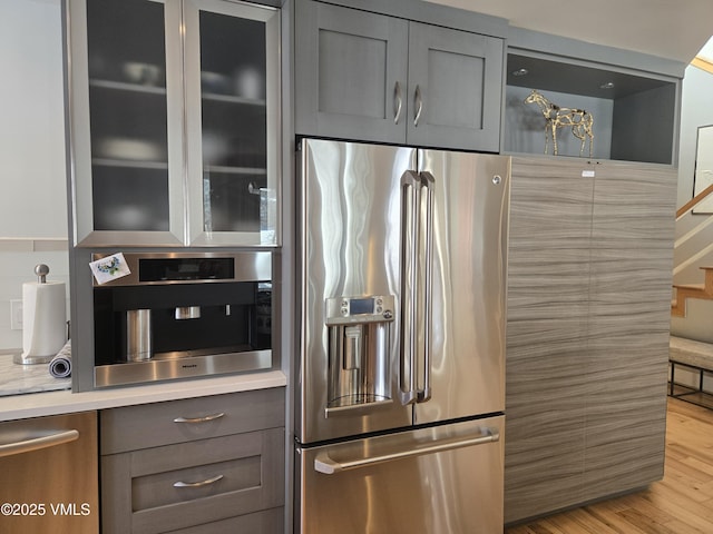 kitchen featuring gray cabinetry, stainless steel appliances, and light wood-type flooring