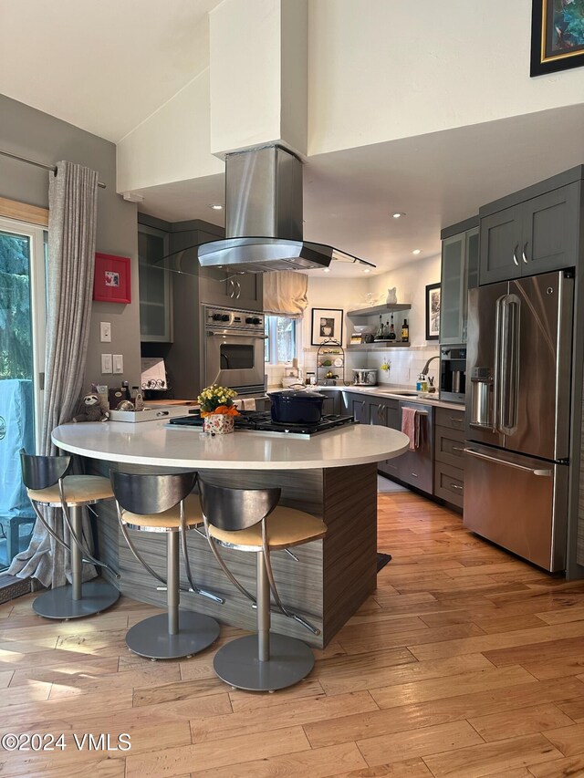 kitchen featuring appliances with stainless steel finishes, light wood-type flooring, a kitchen breakfast bar, and kitchen peninsula