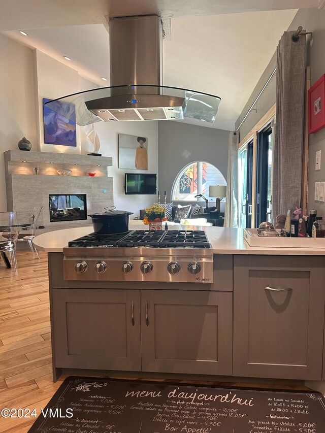 kitchen with island range hood, gray cabinetry, a fireplace, and light hardwood / wood-style floors