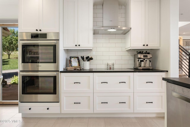 114 Mission Pl, Edwards, CO 81632 - kitchen featuring wall chimney range hood, light tile patterned floors, white cabinetry, backsplash, and stainless steel appliances