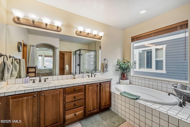 bathroom with double vanity, a garden tub, a shower stall, and a sink