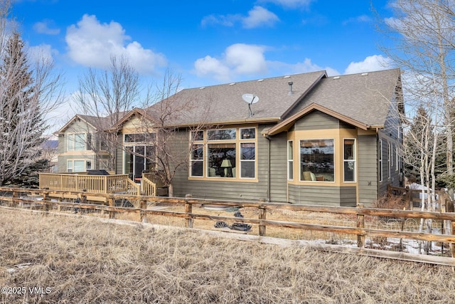 rear view of property with roof with shingles and fence