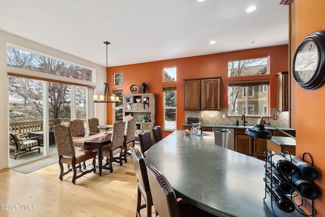 kitchen featuring decorative backsplash, dishwasher, dark countertops, a healthy amount of sunlight, and light wood-type flooring