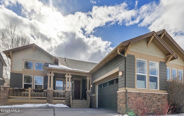 craftsman-style house with covered porch, stone siding, and an attached garage